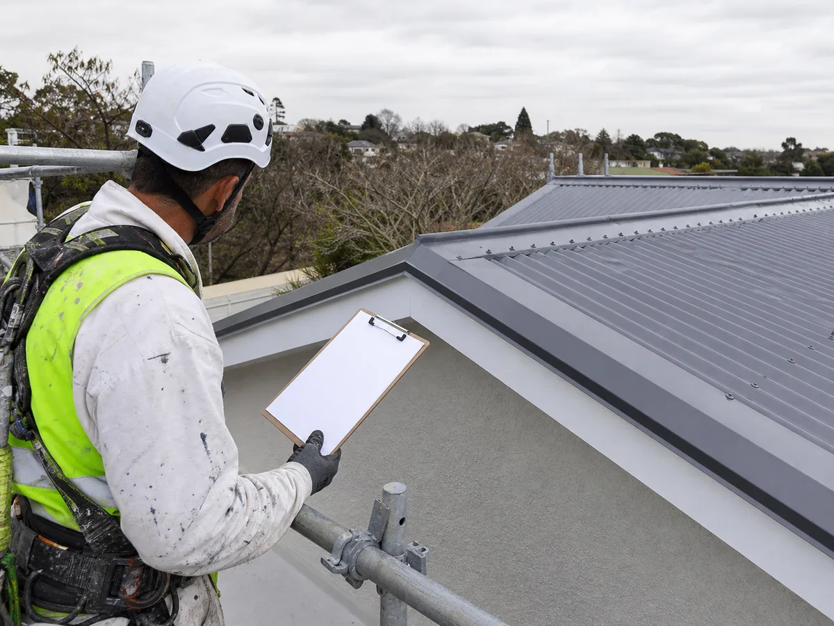 Roof painter documenting workmanship and coating details for an Auckland warranty