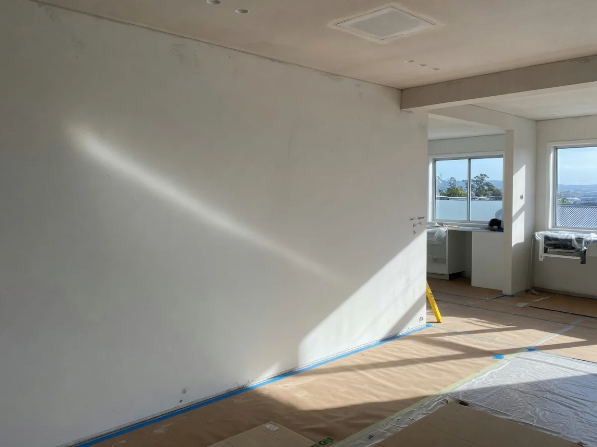 Smooth Level 5 skimmed wall under critical side light in open-plan Auckland living room, Tomar Contracting Auckland